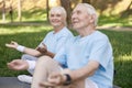 Smiling senior lady looks at relaxed partner meditating together in park Royalty Free Stock Photo