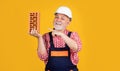 smiling senior man bricklayer in helmet on yellow background