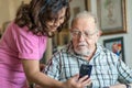 A Smiling senior man and caregiver with smartphone are doing a videocall Royalty Free Stock Photo