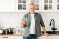 Smiling Senior Man With Glass Of Water In Hand Posing In Kitchen Royalty Free Stock Photo