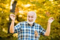 Smiling senior man holding yellow autumn leaves at park. Portrait of handsome old man. Old man alone in autumn park. Royalty Free Stock Photo