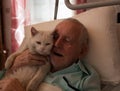 Smiling senior man hugging cat in bed