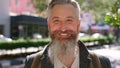 Smiling senior man laughing on a city street. Breaking into a chuckle with a blurred background of restaurants and