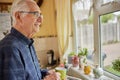 Smiling Senior Man Looking Out Of The Window Holding Cup Royalty Free Stock Photo