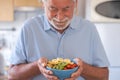 Smiling senior man ready to eat a salad of fresh and dried fruits. Breakfast or lunch time, healthy eating Royalty Free Stock Photo