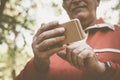 Senior man in sports clothing standing in park and using Royalty Free Stock Photo