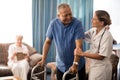 Smiling senior man with walker looking at female doctor