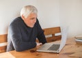 Smiling senior man  wave to camera having video call on laptop, happy elderly male  sit  at home talk using modern technologies Royalty Free Stock Photo