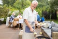 Senior man wearing apron and holding plate of food during garden hoopla Royalty Free Stock Photo