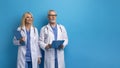 Smiling senior man and woman doctors posing in uniform