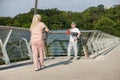 Smiling senior man with mat greets walking woman on footbridge Royalty Free Stock Photo