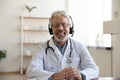 Smiling senior doctor wearing headset looking at camera, telemedicine concept Royalty Free Stock Photo