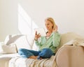 Positive senior woman having video conference on mobile phone with family while relaxing on sofa at home Royalty Free Stock Photo