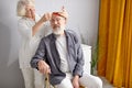 smiling senior wife caring for husband, combing his hair, at home Royalty Free Stock Photo