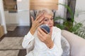 Smiling senior woman applying anti-aging lotion to remove dark circles under eyes. Happy mature woman using cosmetic cream to hide Royalty Free Stock Photo