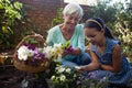 Smiling senior woman carrying flower basket looking at granddaughter Royalty Free Stock Photo