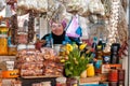 Smiling senior woman at counter of local grocery store with organic produce and yellow tulip bouquet