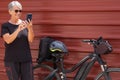 Smiling senior woman cyclist in outdoor excursion in urban city using mobile phone, ejoying healthy lifestyle Royalty Free Stock Photo