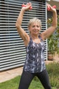 Smiling senior woman is exercising with dumbbells looking at the Royalty Free Stock Photo
