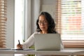 Smiling senior woman in glasses using laptop and making notes on paper. People, technology and remote work concept Royalty Free Stock Photo