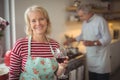 Smiling senior woman holding glass of wine in kitchen Royalty Free Stock Photo