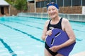 Smiling senior woman holding kickboard at poolside Royalty Free Stock Photo