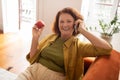 Smiling senior woman holding red apple and enjoying mobile phone call Royalty Free Stock Photo