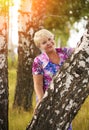 Smiling senior woman holding tree trunk in park Royalty Free Stock Photo