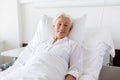 Smiling senior woman lying on bed at hospital ward
