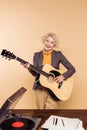 smiling senior woman playing on acoustic guitar near table with vinyl record Royalty Free Stock Photo