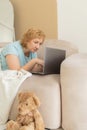 Smiling senior woman relaxing in home bedroom using laptop watching video or movie enjoying technology, leisure time, retirement