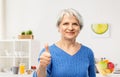 Smiling senior woman showing thumbs up in kitchen Royalty Free Stock Photo