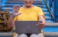 Smiling senior woman sitting outdoors on staircases  using laptop computer. Active blogger worker nomadic people Royalty Free Stock Photo