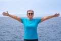 Smiling senior woman standing at the beach with open arms, horizon over water Royalty Free Stock Photo