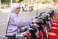 smiling senior woman taking rental bike