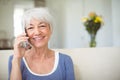 Smiling senior woman talking on mobile phone in living room Royalty Free Stock Photo