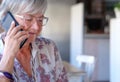 Smiling senior woman talking at mobile phone sitting inside a coffee shop Royalty Free Stock Photo