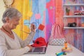 Smiling senior woman using  laptop computer at home, white desktop,  summer accessories on background Royalty Free Stock Photo