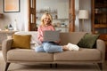 Smiling senior woman using laptop sitting on comfy sofa indoor Royalty Free Stock Photo