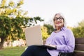 smiling senior woman using laptop sitting on park Royalty Free Stock Photo