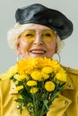 smiling senior woman in yellow leather jacket with bouquet of yellow flowers, Royalty Free Stock Photo