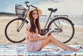 Smiling sensual young woman holds a book and looking at camera while sitting on the beach, enjoying the vacation. Royalty Free Stock Photo