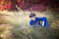 Smiling seven year old boy portrait sitting in field in Autumn