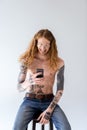 smiling shirtless tattooed man with curly hair looking at smartphone Royalty Free Stock Photo