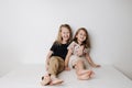 Smiling siblings sitting together on table. Boy hugs girl, she leans away a bit.