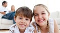 Smiling siblings lying on the floor