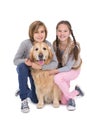 Smiling siblings petting their golden retriever