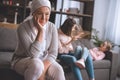 smiling sick mature woman in kerchief looking away while family members having fun