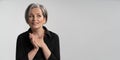 Smiling silver haired woman dreams clasped hands. Caucasian mature woman in black blouse looking to right side with copy