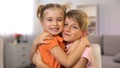 Smiling sister and brother embracing and looking at camera at home, happiness